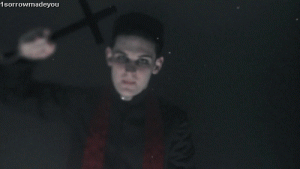 Priest exorcising demon with cross